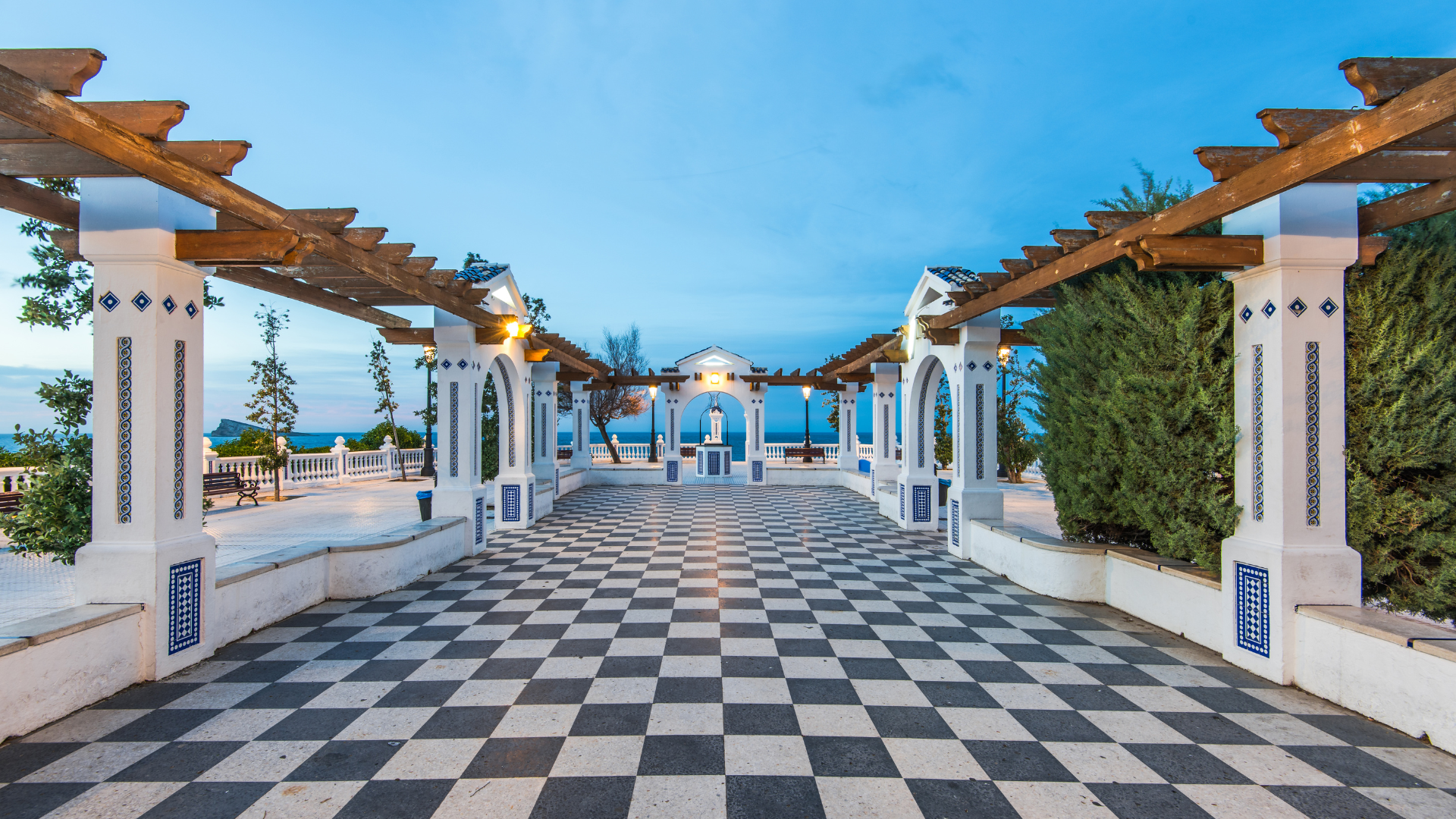 Seaside terrace with checkerboard floor, arched pergola and central shrine overlooking sea
