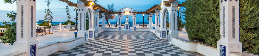 Seaside terrace with checkerboard floor, arched pergola and central shrine overlooking sea