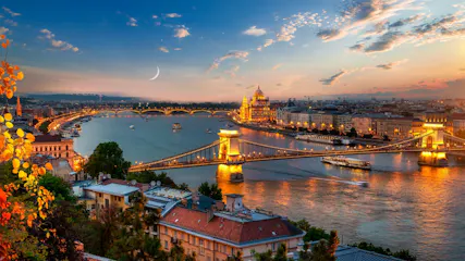 Budapest dusk panorama: illuminated Chain Bridge over the Danube and lit Parliament, crescent moon