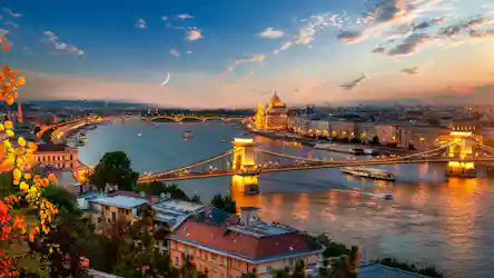 Budapest dusk panorama: illuminated Chain Bridge over the Danube and lit Parliament, crescent moon