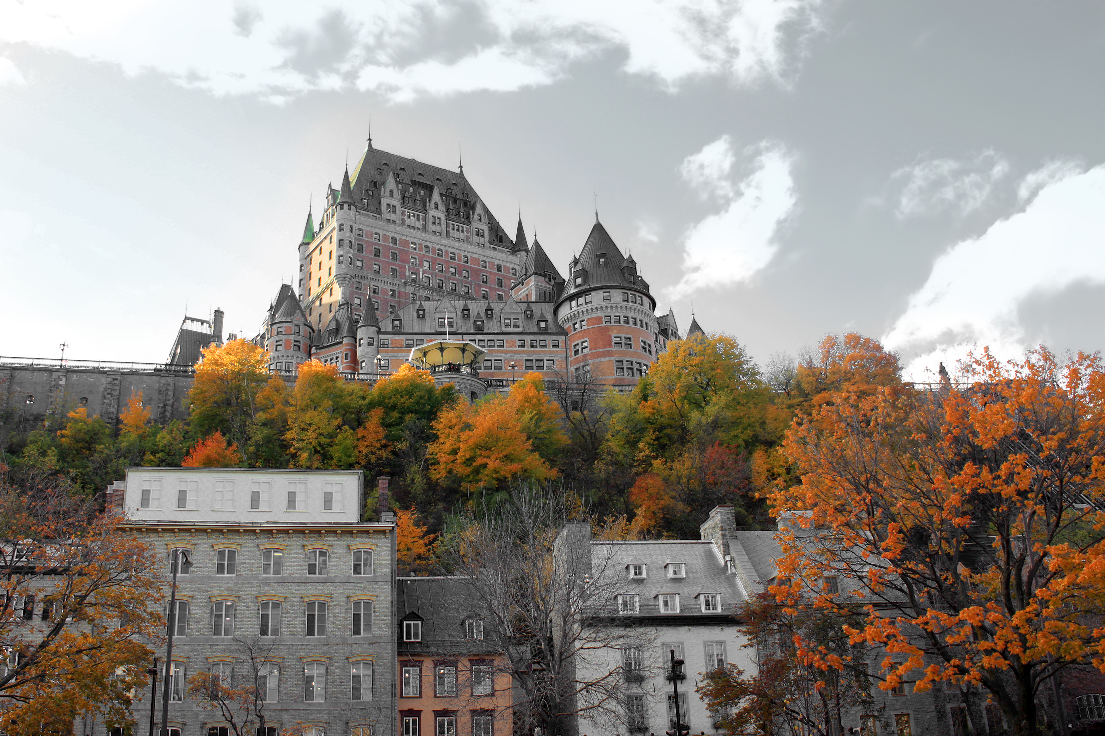 Historic château-style hotel landmark with steep turrets atop a hill, autumn trees and stone town below