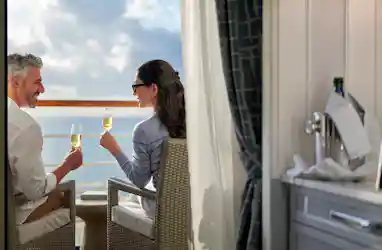 Middle-aged couple on a cruise balcony toasting champagne, ocean horizon beyond