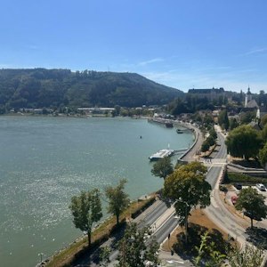 Riverside town with curving road, river docks, tree-lined embankment, hillside and church steeple