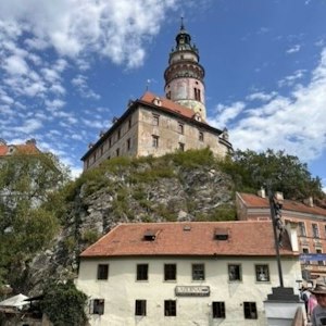 Historic castle tower on rocky hill above red-roofed town, a scenic tourist landmark