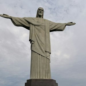 Christ the Redeemer statue in Rio de Janeiro, arms outstretched against a cloudy sky