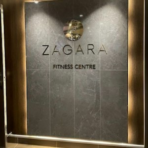 ZAGARA Fitness Centre sign in metallic letters on gray marble wall with round floral logo