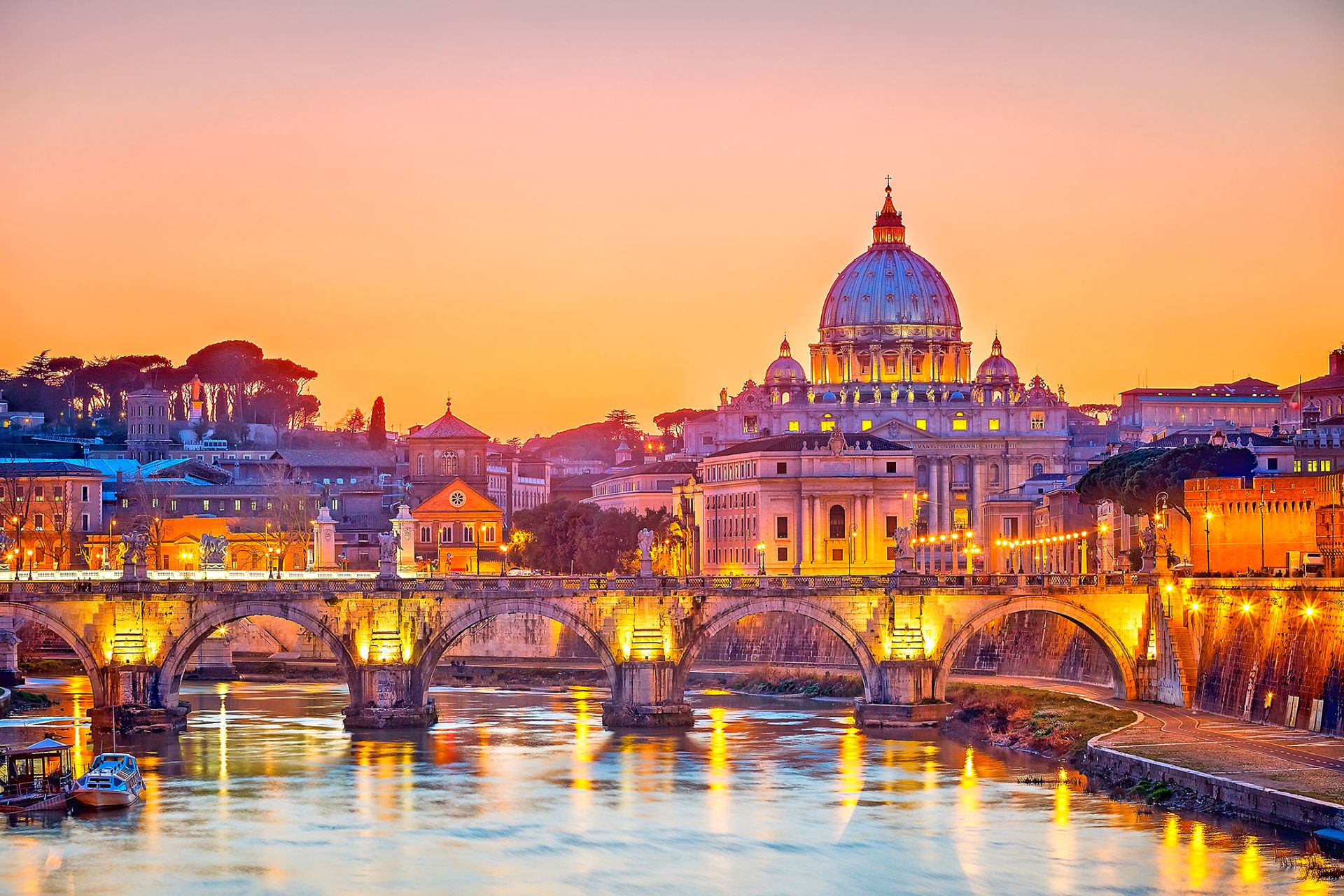 St. Peter’s Basilica dome and illuminated bridge reflecting on the Tiber River at sunset