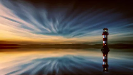 Lone red-and-white lighthouse reflected in calm water under streaked blue and gold sunset sky