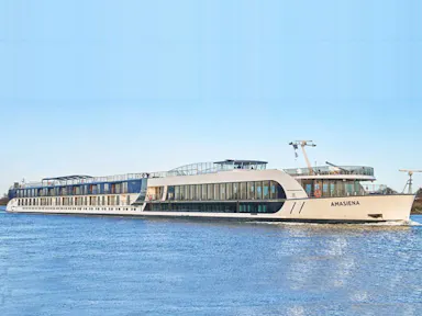 White multi-deck river cruise ship AMASIENA sailing on calm blue water with sun decks.