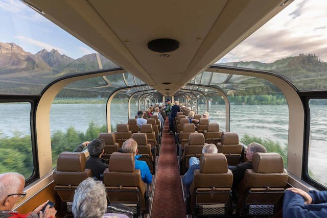 Train car interior with see-through roof looking out at mountains