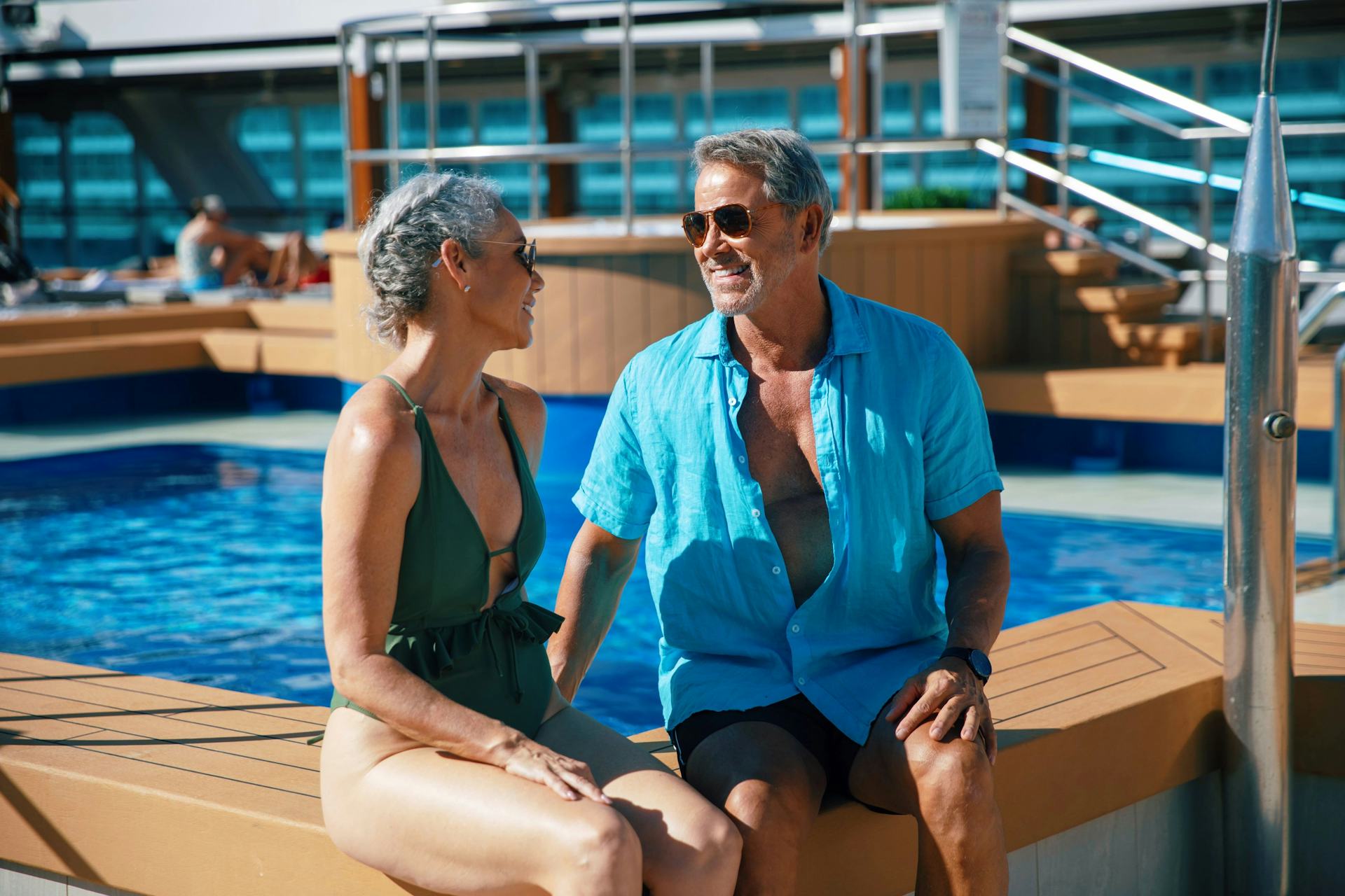 Two people in bathing suits talking next to a pool.
